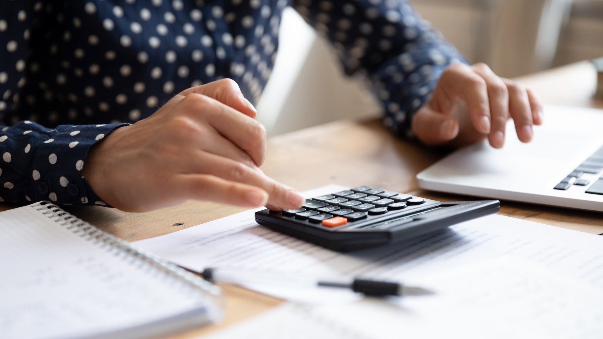 Woman using calculator counting finances calculate bills pay online, closeup